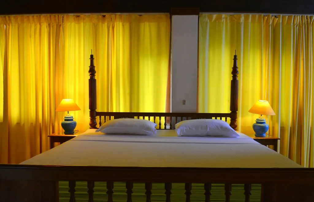 Four-poster bedroom with yellow drapes at Cavala, Baga