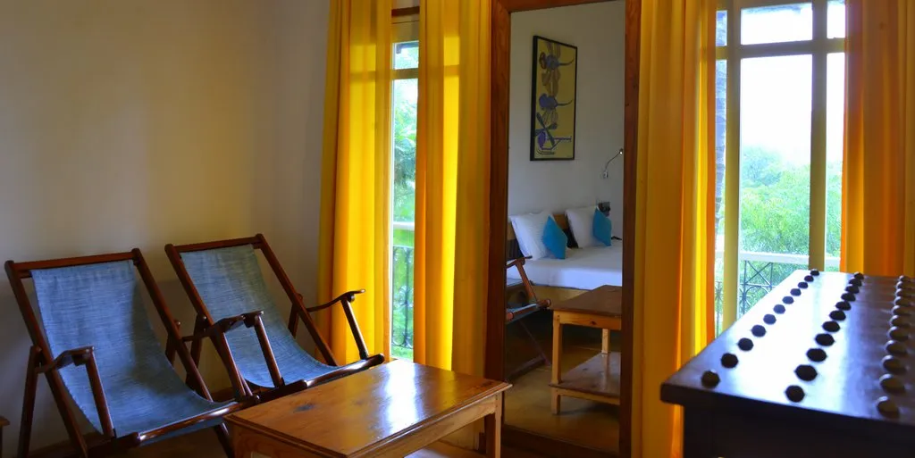 Room sitting area with planter's chairs and a garden view at Cavala